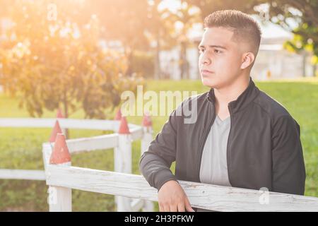young male student by the wooden fence thinking about his future and thinking about his business, entrepreneur happy for his achievements, with beauti Stock Photo