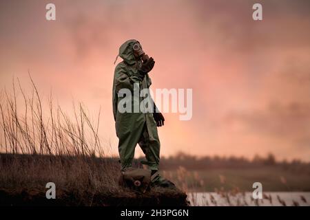 A man in a gas mask and protective suit stands on the edge of the abyss. Stock Photo