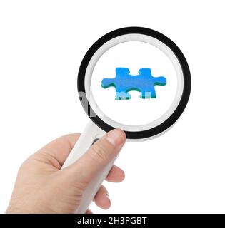 Hand with magnifying glass and puzzle Stock Photo