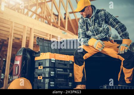 Caucasian Construction Worker Taking Short Break While Working on House Framing. Contractor Seating on His Pickup Cargo Bed. Stock Photo
