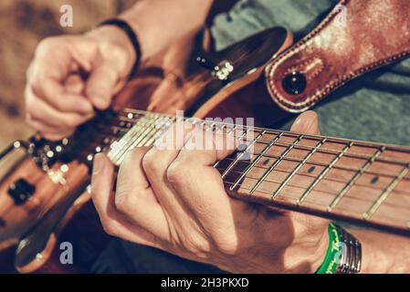 Caucasian Musician Playing Electric Guitar Close Up Photo. Music and Entertainment Industry Theme. Stock Photo