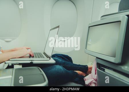 Caucasian Woman Remotely Working on Her Laptop Computer While in Airplane Business Class. Using On Board Internet Access. Stock Photo