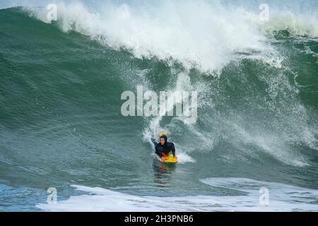 Surfing at Portrush as a big wave storm comes in off the Atlantic Ocean and hits the Antrim Coast, Northern Ireland. Stock Photo