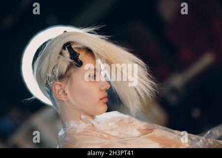 Young woman hairdresser dying hair at beauty salon. Professional hair roots coloring Stock Photo