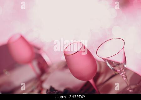Two empty champagne glasses, pink champagne on table with sparkles bokeh lights on a background Stock Photo