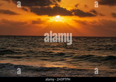 Sunset on the Mediterranean Sea. The sun's rays are reflected through the clouds in the water. Stock Photo