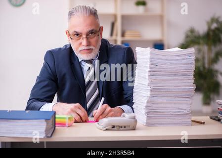 Old businessman employee unhappy with excessive work in the office Stock Photo