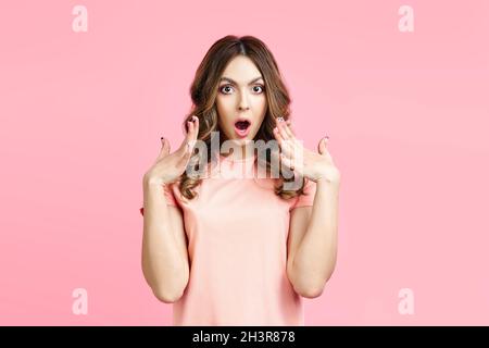 Portrait of amazed surprised woman on pink background Stock Photo