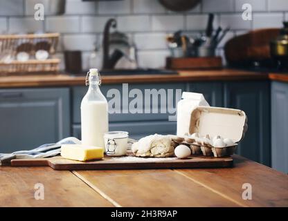 Assorted ingredients for pastry preparation placed on wooden chopping board on table in kitchen Stock Photo