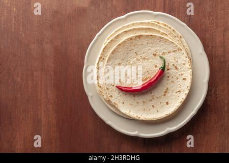 A red chilli pepper, shot from the top on a pile of tortillas, Mexican flatbreads Stock Photo