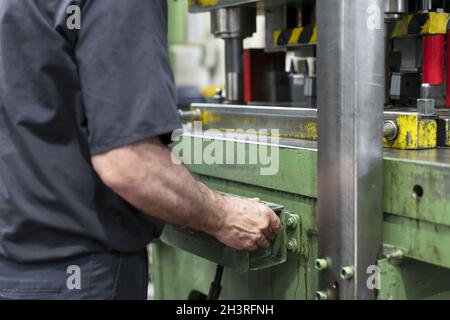 Steel Manufacturing Plant. A Worker is Placing a Piece of Metal Inside the Press. The Press is pushed Down. Metallurgy. Producti Stock Photo