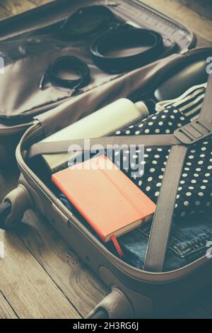 Open suitcase full of clothes isolated on wooden background Stock Photo