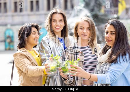 Lifestyle outdoor group of multiethnic beautiful young women clinking cocktail glasses celebrating life love happiness friendshi Stock Photo