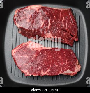 Two raw pieces of beef in a black square grill pan Stock Photo