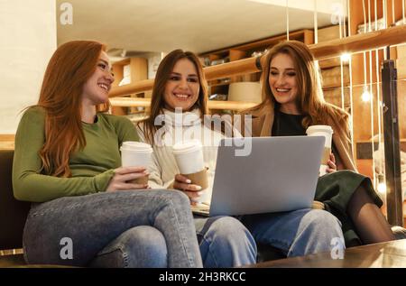Happy girlfriends using laptop in cafe Stock Photo