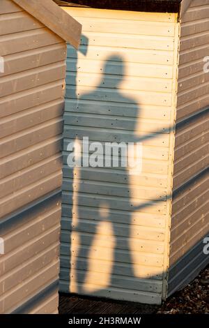 mans shadow in evening sunlight on white beach hut Stock Photo
