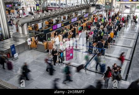 Stuttgart, Germany. 30th Oct, 2021. Passengers stand with their luggage at check-in counters at Stuttgart Airport at the start of the autumn holidays in Baden-Württemberg. Airports are a little busier again, but they are still a long way from their pre-Corona load factors. Credit: Christoph Schmidt/dpa/Alamy Live News Stock Photo