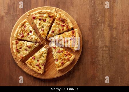 Slices of a cut quiche pie, shot from the top on a dark rustic wooden background Stock Photo