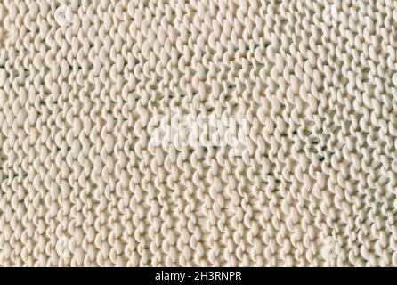 Knitted real woolen cotton fabric light background. Warm light woolen braids are knitted with threads background. Stock Photo