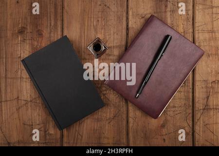 A black book, a leather journal, and ink well and pen Stock Photo