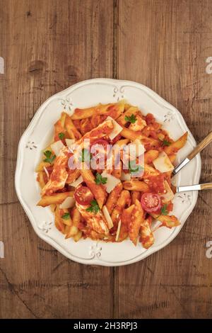 Penne pasta with tomato sauce, fork and spoon plunged into plate Stock Photo