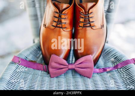 Brown leather groom shoes and an untied bow tie. Stock Photo