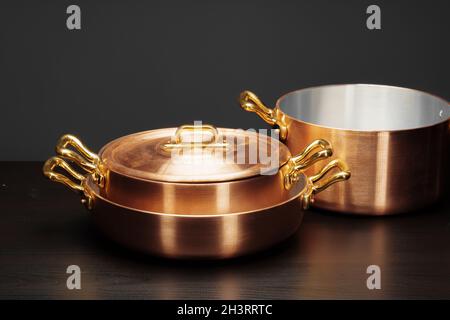 Shiny vintage copper cookware over dark background Stock Photo