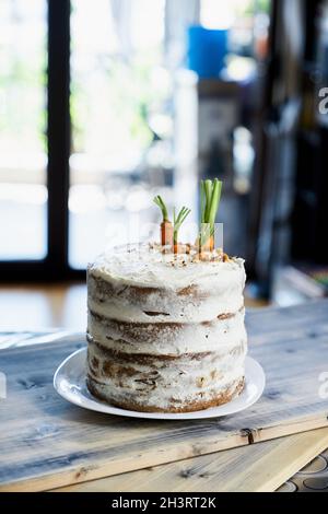 Carrot cake stands on a white plate on the table in the kitchen Stock Photo