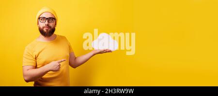 stylish bearded man point at storage cloud over yellow background, storage concept, panoramic layout with space for text Stock Photo