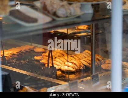 Delicious traditional Cornish pasty pies cooking and on display in shop window. Rows of pasties and pies under heat lamp ready to buy and eat. Stock Photo