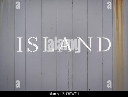 The word island written in white text on a wooden textured door in grey paint. Stock Photo