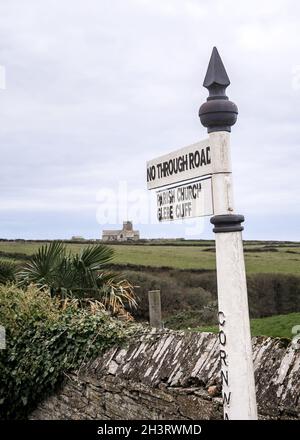 Traditional old white retro metal sign pointing to cliff path and church in village near Glebe Cliff in Cornwall South West England. Beautiful rural Stock Photo