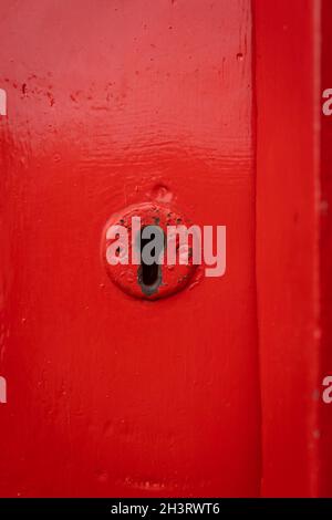 Red old lock key hole in wooden door painted bright retro historic red. Stock Photo