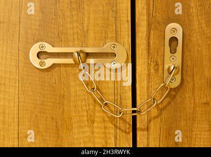 Additional security lock with chain and sliding on wooden door. Stock Photo