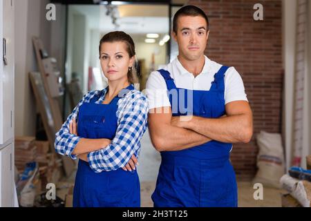 Portrait of smiling man and woman in work overalls in room during finishing work Stock Photo