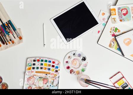 Desk of an illustrator with digital tablet watercolors and drawings Stock Photo