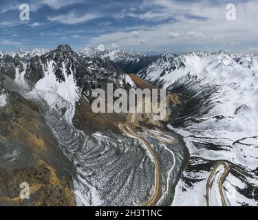 Winding dirt road in the snow mountains Stock Photo