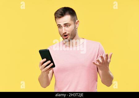 Shocked funny millennial man using mobile phone Stock Photo