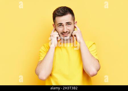 Handsome funny man covering his ears with hands afraid to hear bad news Stock Photo