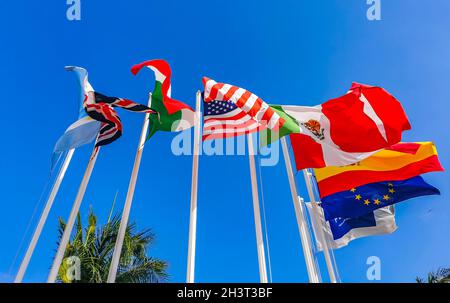 Flags of many countries like argentina spain united states canada italy and europe with blue sky and palm trees in Playa del Carmen Mexico. Stock Photo