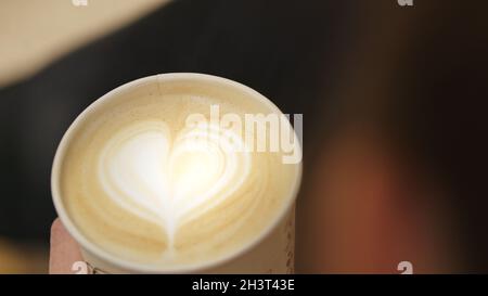 Woman holding cup of cappuccino with heart. Love for coffee concept. High quality photo Stock Photo