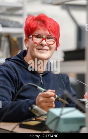 Industrial worker woman soldering cables of manufacturing equipment in a factory Stock Photo