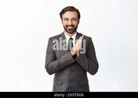 Image of pleased handsome businessman rubbing his hands, smiling satisfied, getting to business, standing over white background Stock Photo