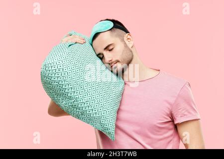 Young handsome man sleeping holding pillow in hands Stock Photo