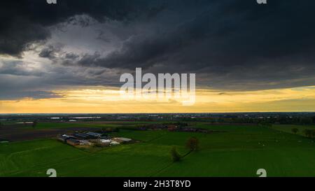 Aerial landscape of countryside with colorful storm clouds. Extreme thunderstorm over a farm and agricultural fields and road. Stock Photo