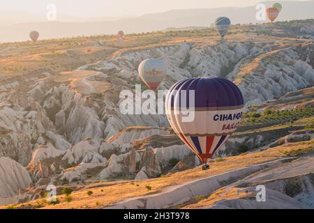 GOREME, TURKEY - AUGUST 3, 2021: Close up of colorful hot air balloon with basket full of tourists flying very close to the ground over the Cappadocia Stock Photo