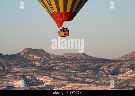 GOREME, TURKEY - AUGUST 3, 2021: Close up of one lonely colorful hot air balloon flying over the Cappadocia valley in the morning light Stock Photo