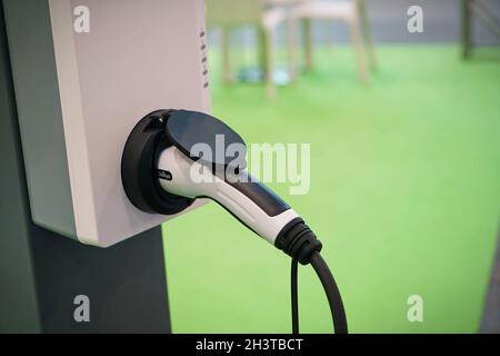 Power cable pump plug in charging power to electric vehicle EV car with modern technology UI control information display, car fueling station connecte Stock Photo