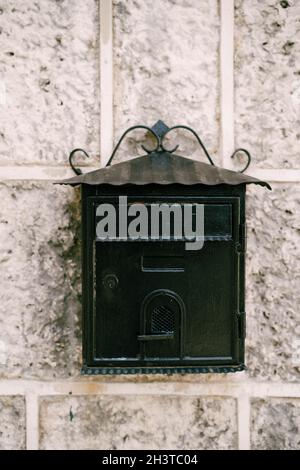 Close-up of a black metal mailbox on a stone wall. Stock Photo