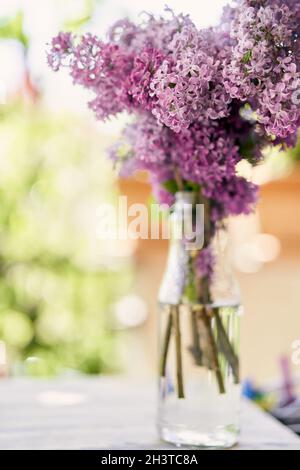 Bouquet of lilacs stands in a bottle on the balcony Stock Photo